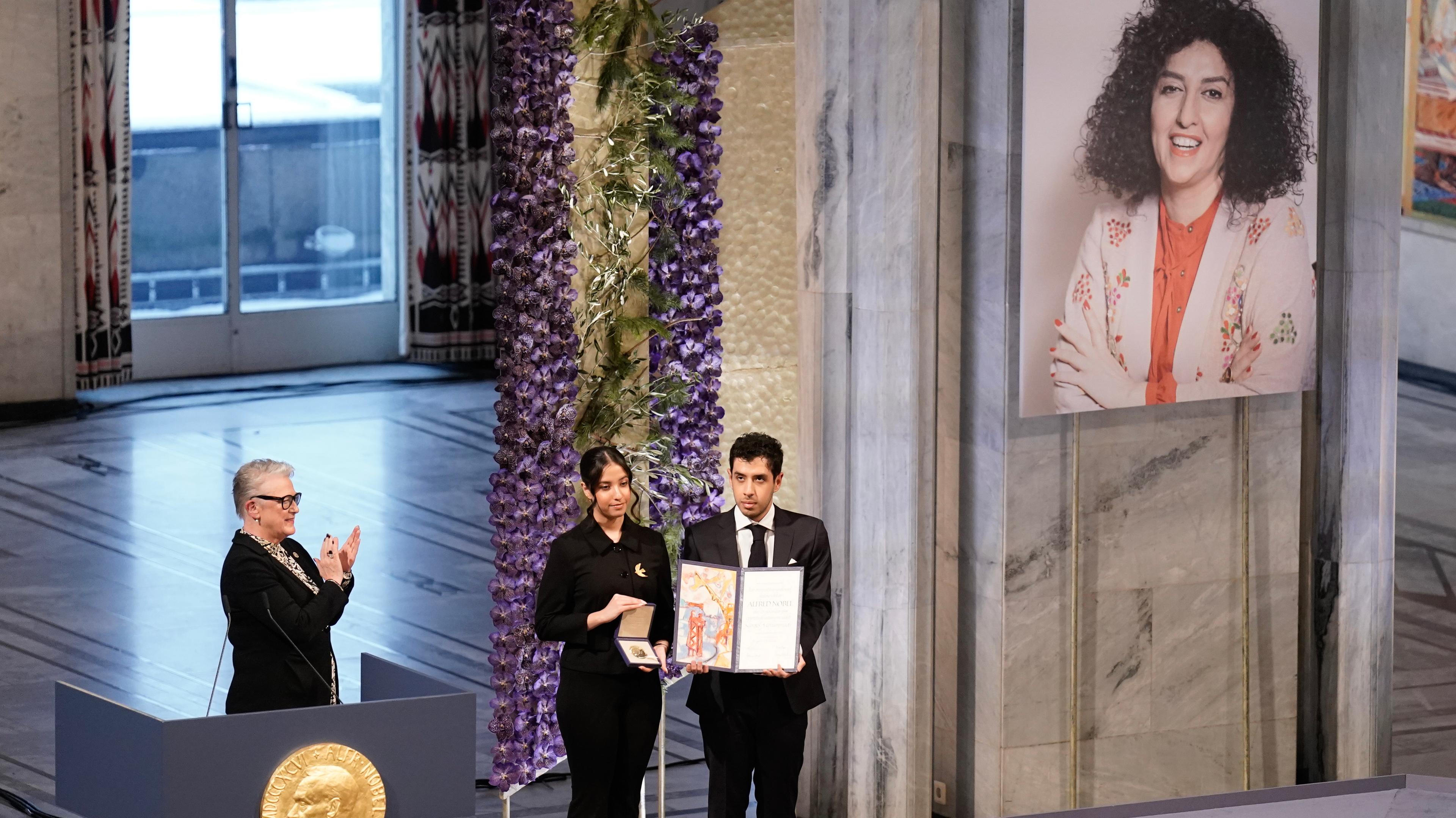 Ali (r) und Kiana Rahmani (M) halten die Medaille und die Urkunde während der Verleihung des Friedensnobelpreises 2023 im Rathaus von Oslo entgegen