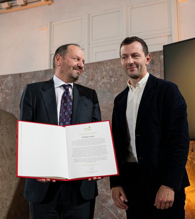 Philippe Sands, und Sebastian Guggolz, Vorsteher des Börsenvereins des Deutschen Buchhandels, stehen während der Preisverleihung auf der Bühne.