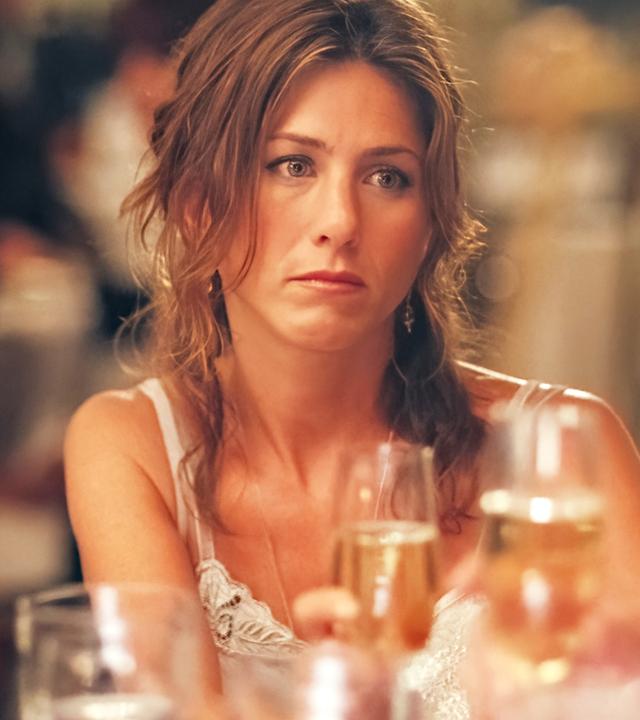 "Friends With Money": Olivia (Jennifer Aniston) sitzt an einem Tisch voller Gläser und schaut frustriert ins Leere.