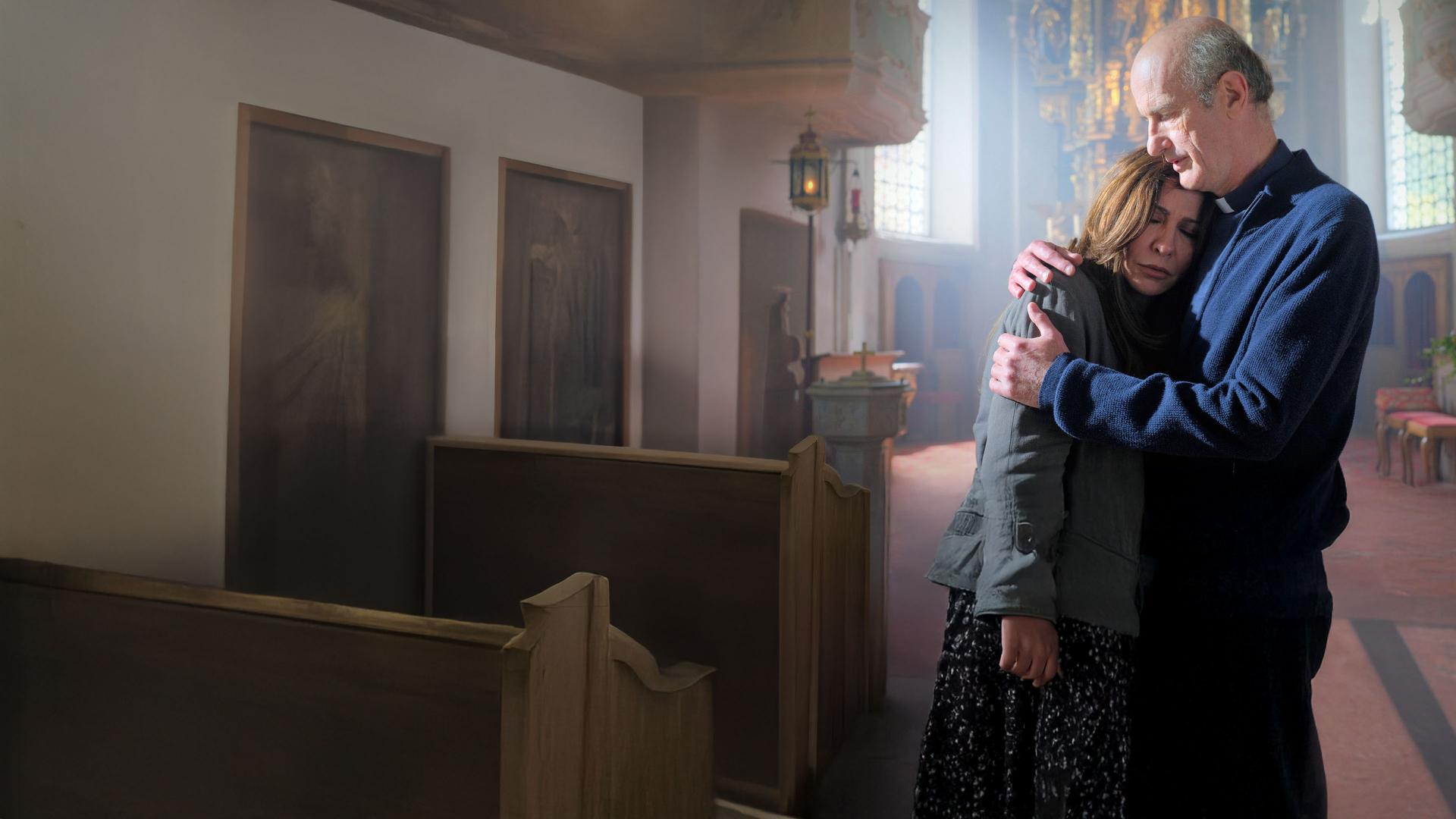 "Frühling - Am Ende des Sommers": Pfarrer Sonnleitner (Johannes Herrschmann) hält in der Frühlinger Kirche Katja Baumann (Simone Thomalla) tröstend im Arm. Sie hat die Augen geschlossen.