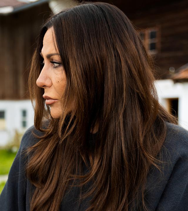 Theo Neumeister (Valentin Just) sitzt mit Katja Baumann (Simone Thomalla) auf einer Bank vor dem Bauernhof.