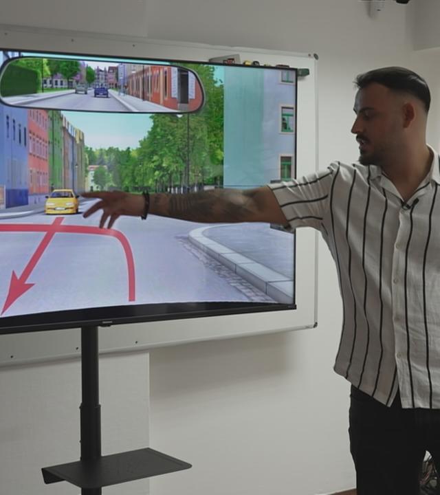 Ein Fahrlehrer erklärt im Theorie-Unterricht am Bildschirm eine Verkehrssituation.