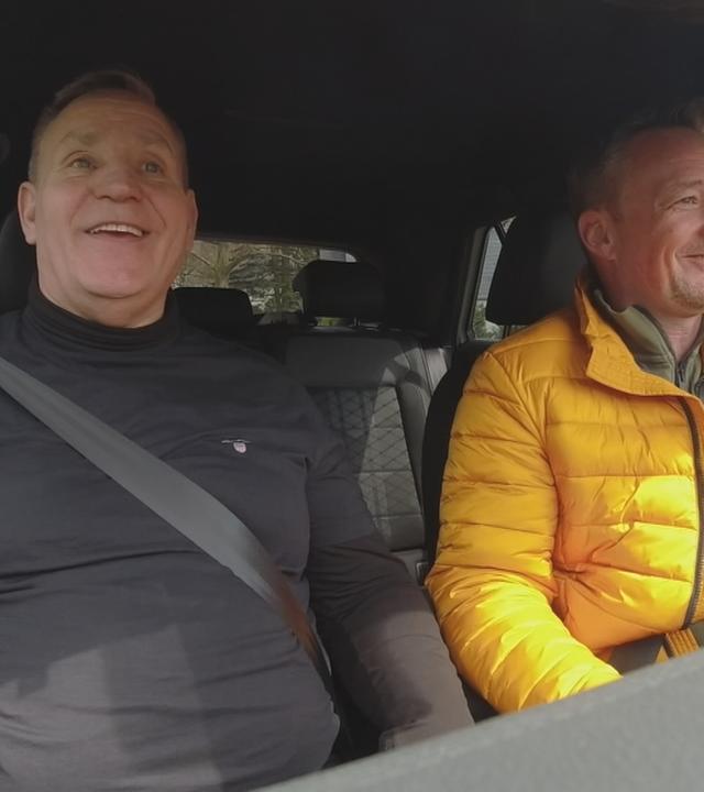 ZDF-Reporter Henning Behrens sitzt mit Fahrschullehrer im Auto