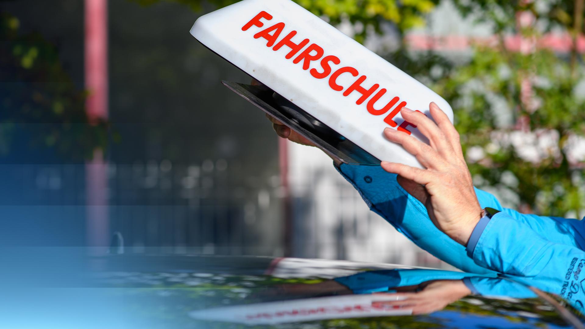 Das Dach eines Fahrschulautos, auf dem das "Fahrschule"-Schild gerade platziert wird