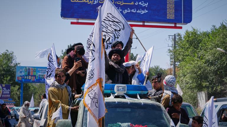 Anhänger der Taliban-Regierung fahren auf einem Fahrzeug in Kabul.