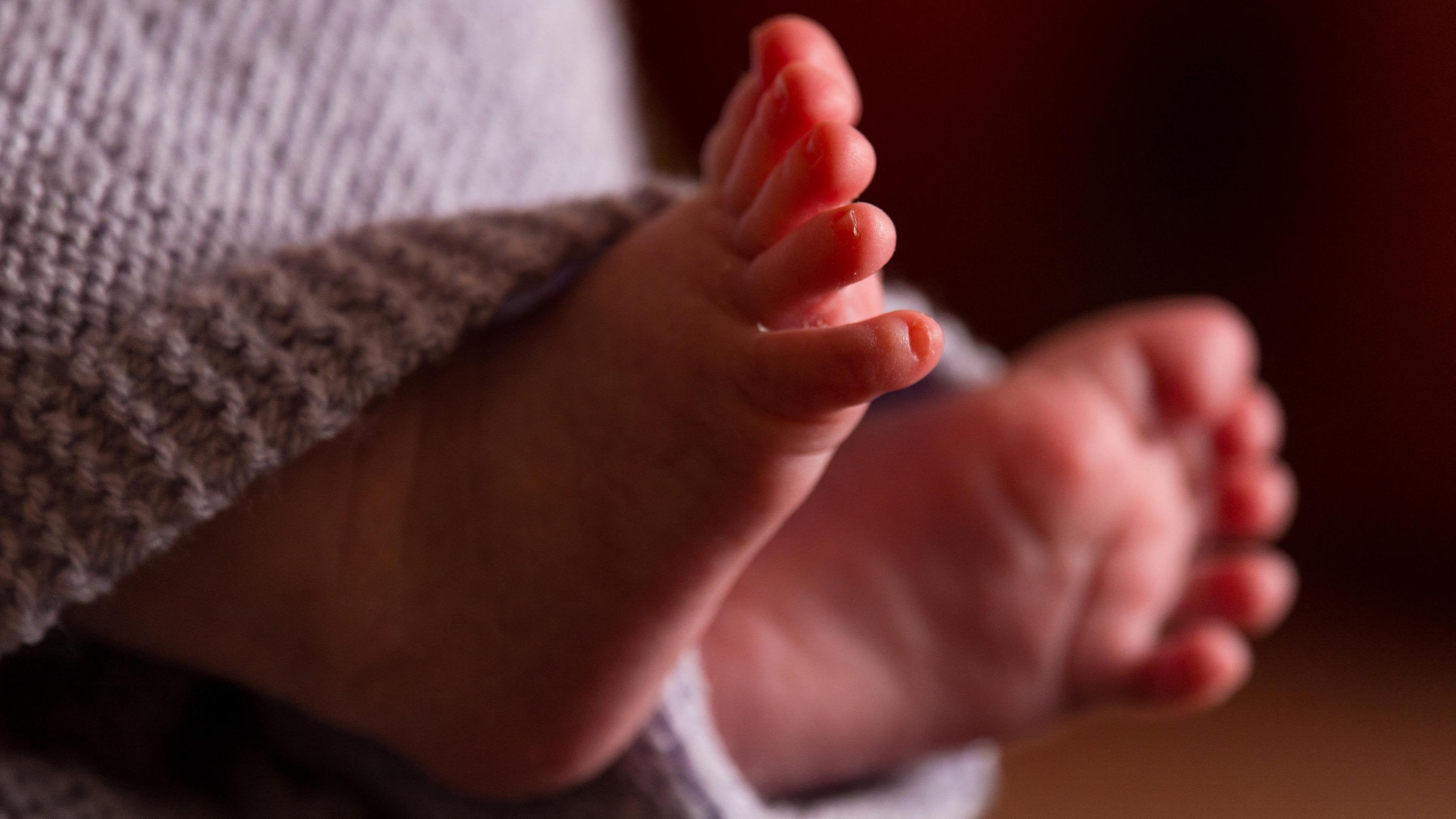 Füße eines Neugeborenen, eingewickelt in eine Decke. 