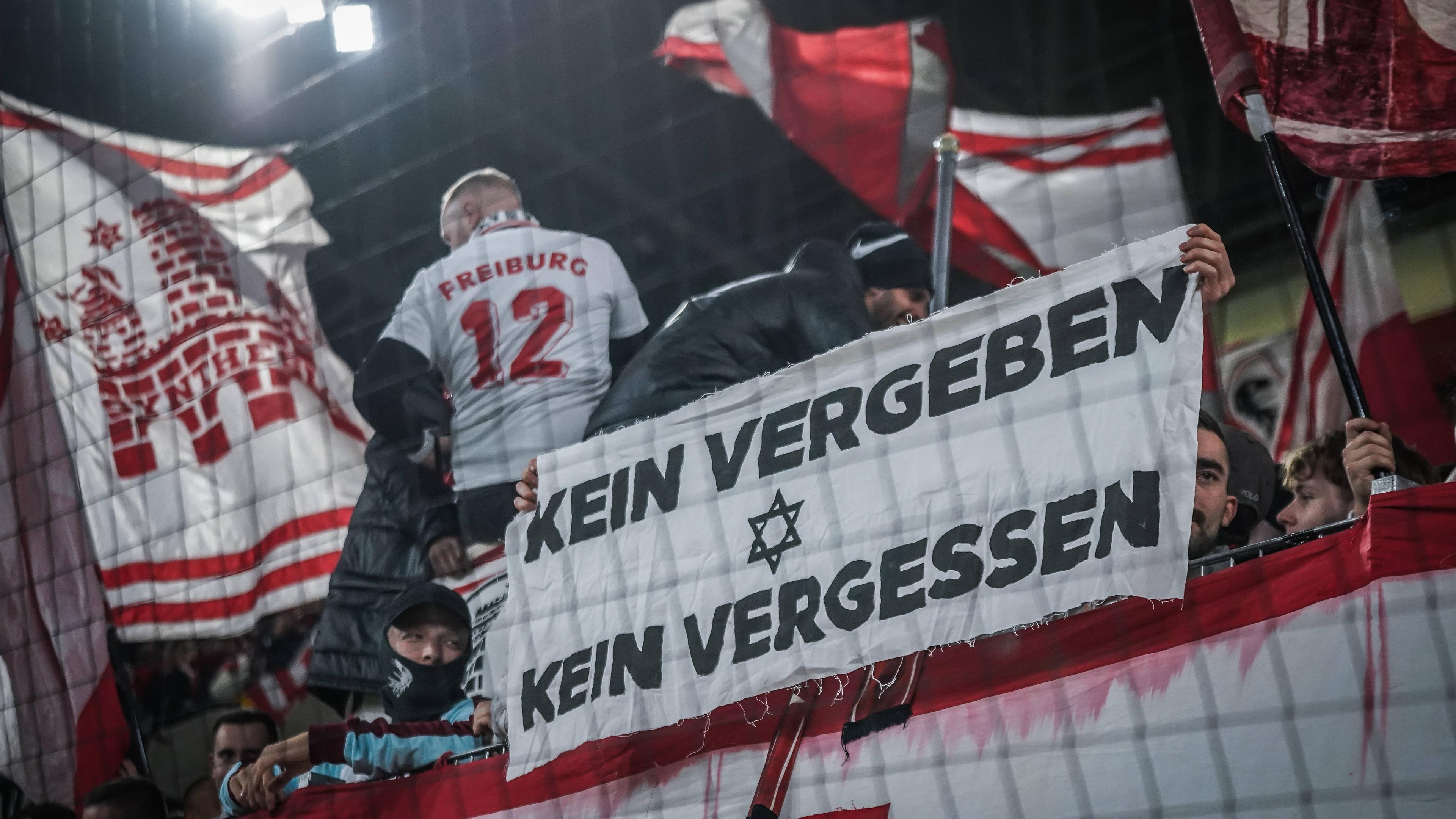Tribüne des SC Freiburg zeigen ein Banner mit KEIN VERGEBEN KEIN VERGESSEN mit einem Davidstern 