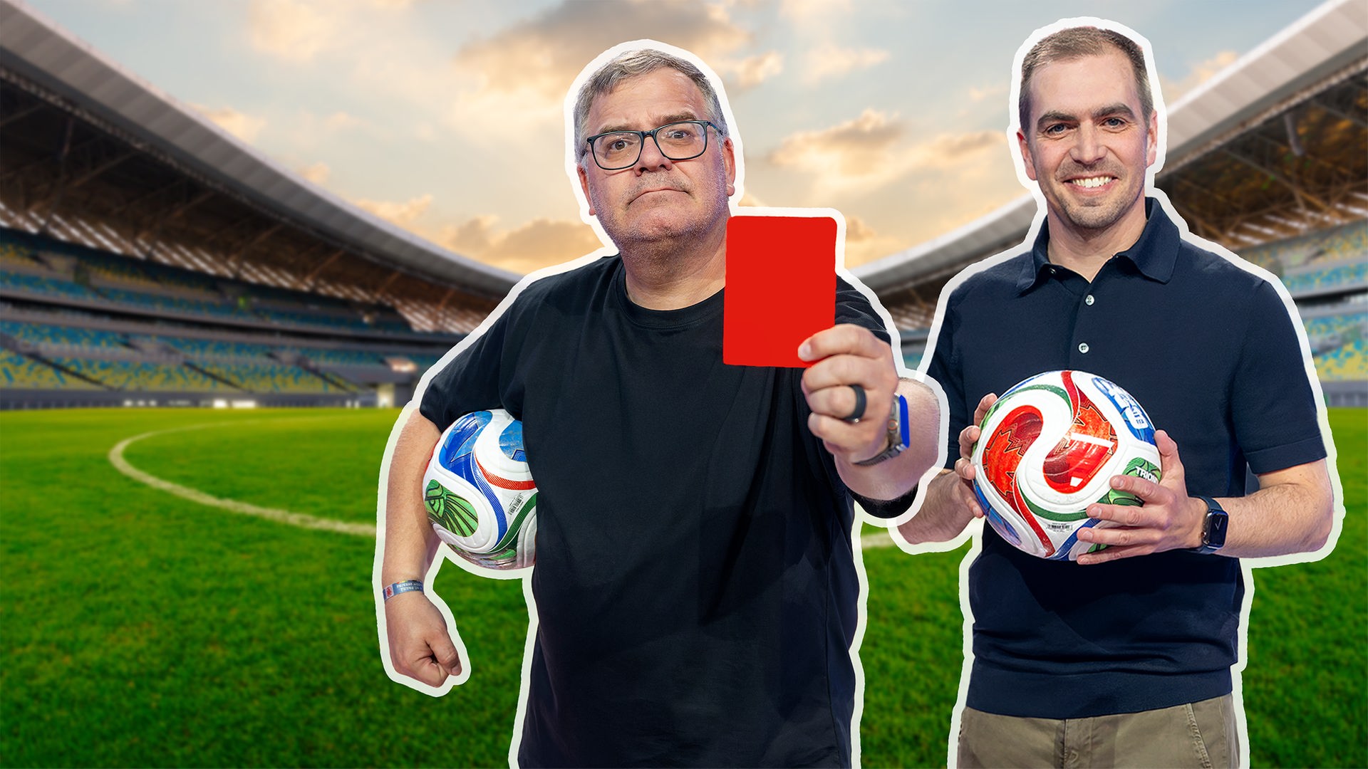 Das Bild zeigt Moderator Elton und den ehemaligen Profifußballer Philipp Lahm in einem Fußballstadion. Elton steht im Vordergrund, hält einen Fußball unter dem Arm und streckt eine rote Karte in die Kamera, während Lahm daneben steht, einen Ball in den Händen hält und freundlich lächelt.