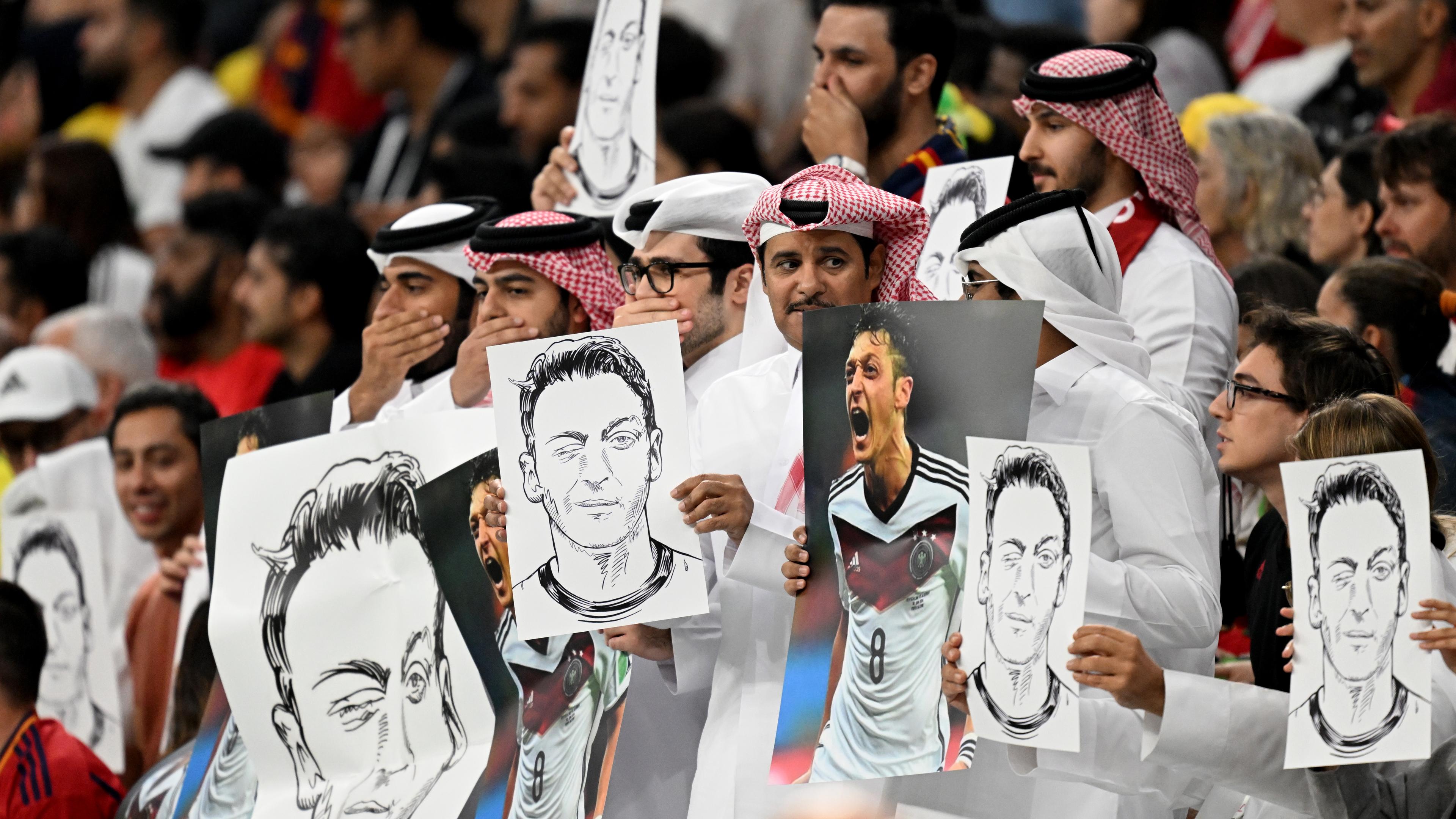 Katar, Al-Chaur: Zuschauer halten Bilder von Deutschlands ehemaligem Nationalspieler Mesut Özil in die Höhe.