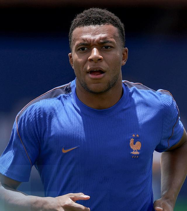 Fußballspieler Mbappé in einem blauen Frankreich-Trikot. Er läuft gerade und sieht deutlich angestrengt aus.