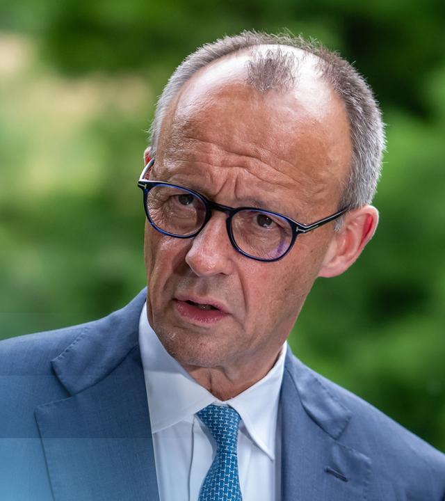 Bundeskanzler Friedrich Merz vor einem Logo der G7