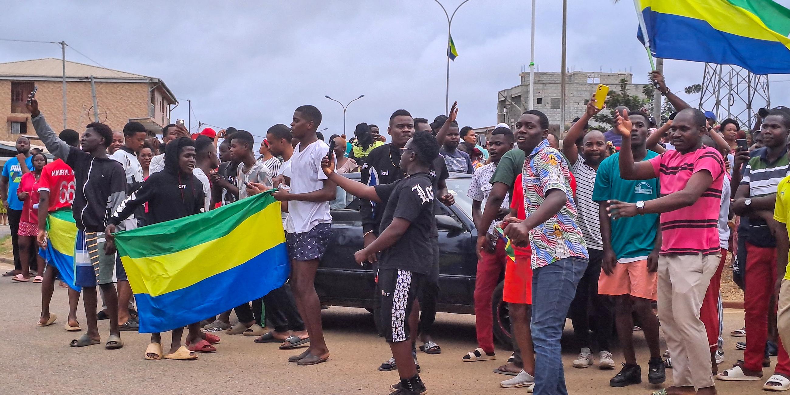 Menschen zeigen die gabunische Nationalflagge, während sie in den Straßen von Akanda, Gabun, feiern, aufgenommen am 30.08.2023