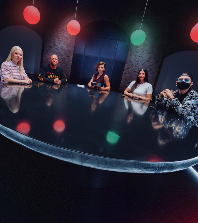 Moderatorin Clara Westhoff (Mitte) sitzt mit den vier Gästen (Jette Nietzard, Etienne Steffen, Meltem Seker und Jay Riddle) der DEEP DEBATE-Folge "Wann geht Cancel Culture zu weit?" an einem großen Runden Tisch. Über ihnen hängen vier runde Lampen, von denen drei rot und eine grün leuchtet.