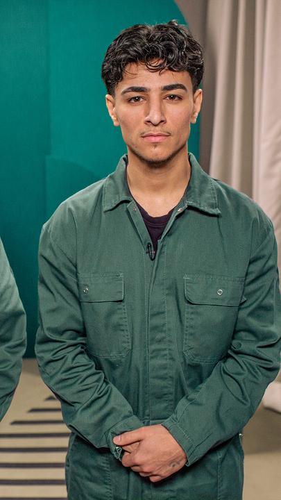 Ein junger Mann und eine junge Frau stehen nebeneinander und blicken in die Kamera. Beide tragen den selben grünen Overall.