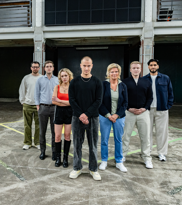 Es stehen sieben Menschen auf einem Boden, der ein schachbrettartiges Muster hat. Die sechs Gäste der 13 Fragen Folge „Stolz auf Deutschland – darf man das heute noch?“ und Moderator Wyn Matthiesen blicken in die Richtung des Betrachters.