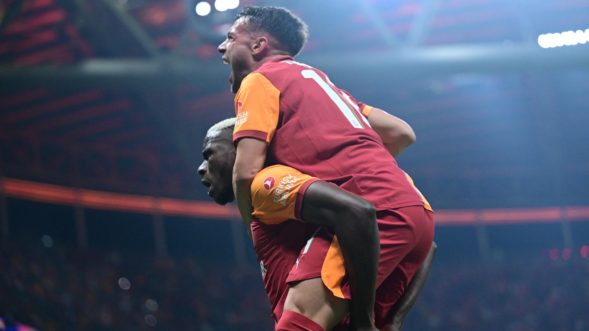 Galatasarays Torschütze Victor Osimhen nimmt einem Mitspieler huckepack und jubelt.
