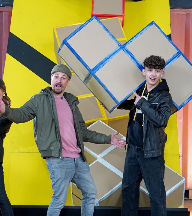 Checkpoint: Das Testteam und Tommy Schell stehen hinter einem Tisch, auf dem eine Flammenreihe aufgebaut ist. 