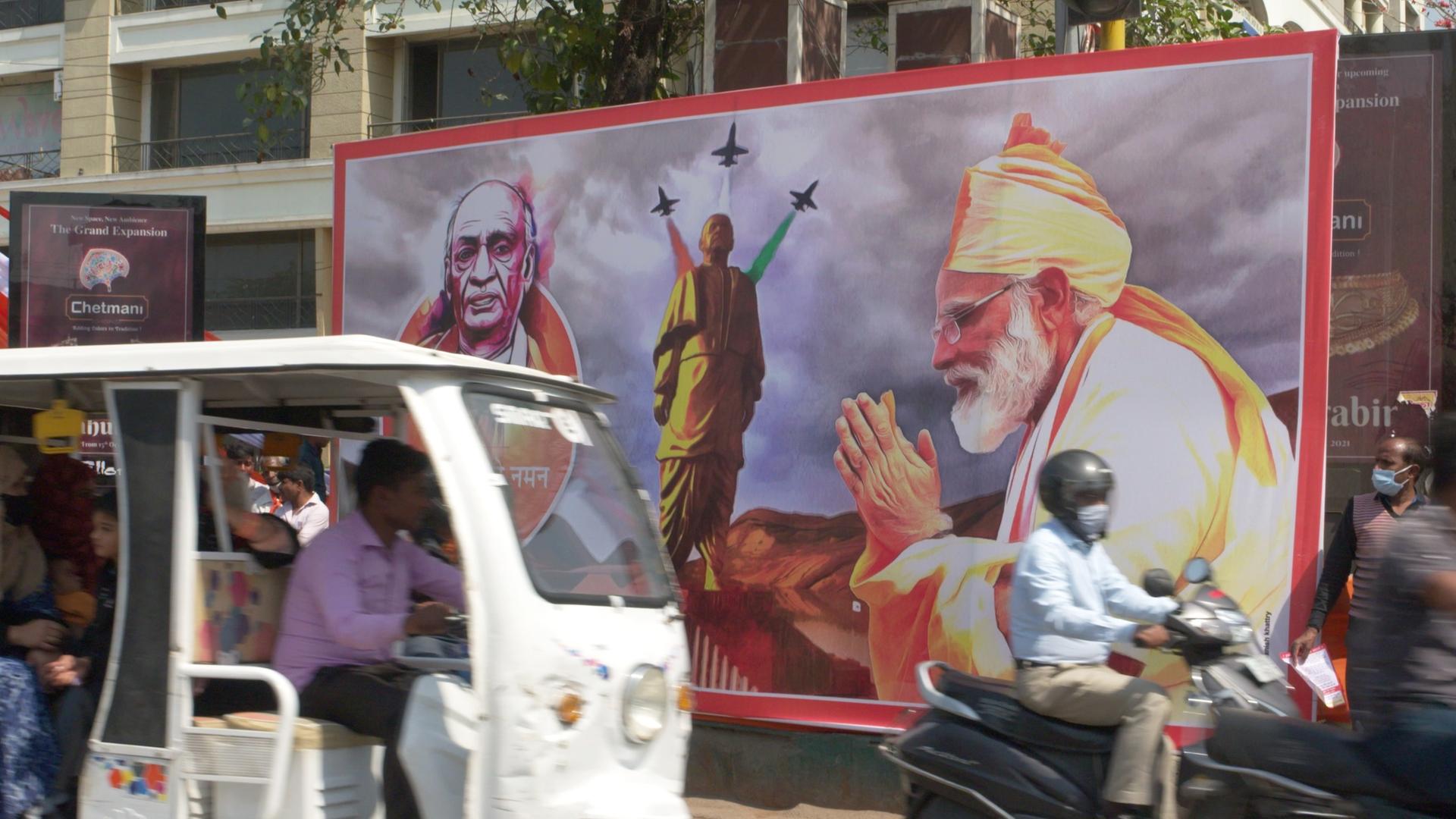  Straßenszene mit Mopeds, großes Wahlplakat der Regierungspartei BJP, auf dem Premierminister Narendra Modi zu sehen ist.