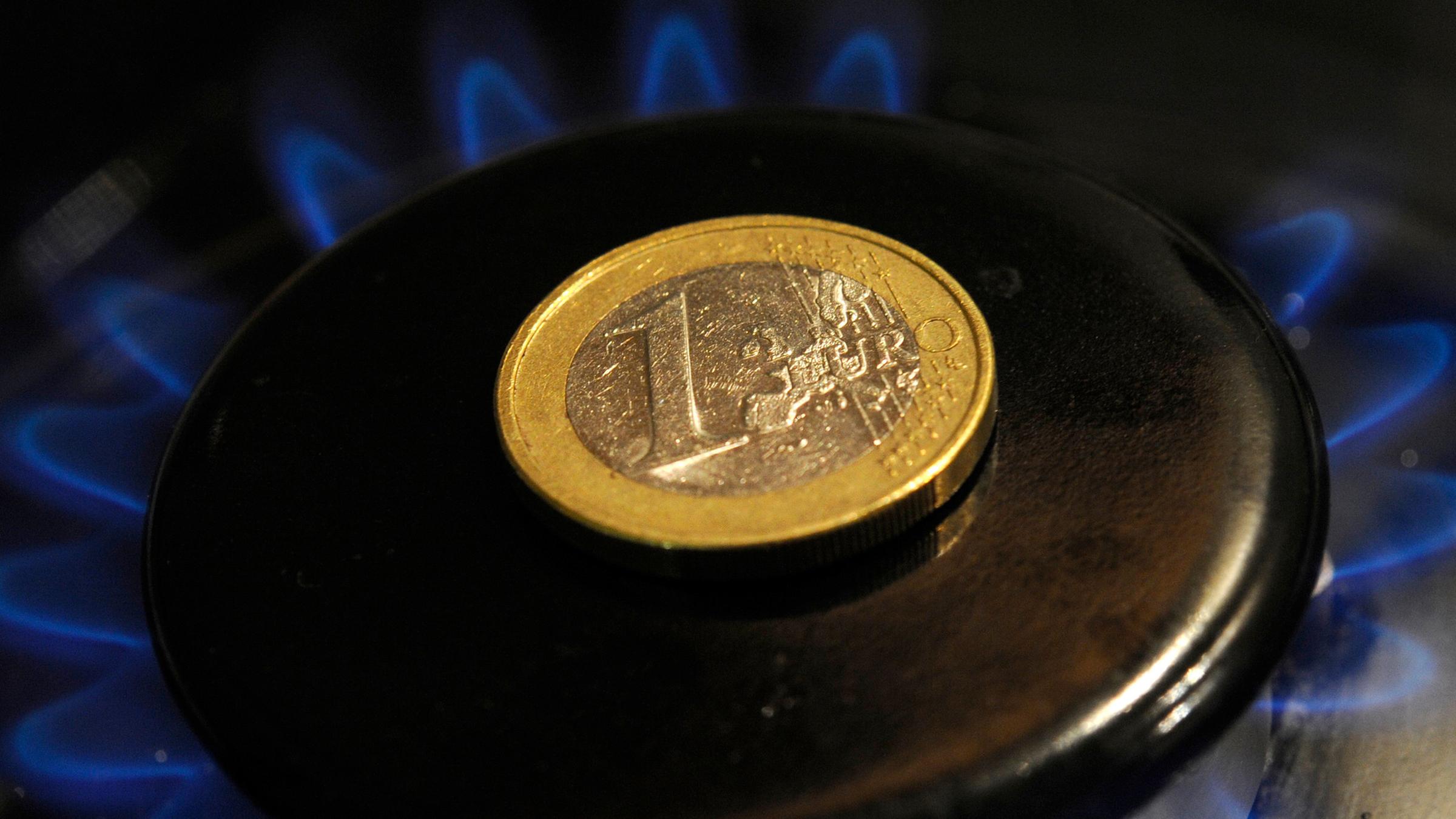 Ein-Euro-Münze liegt auf brennender Gas-Herdflamme