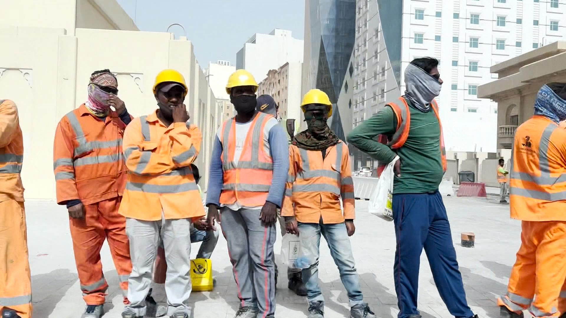 Mehrere Gastarbeiter stehen am Straßenrand in katar