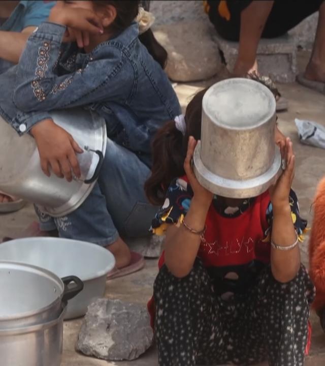 Kinder warten mit Töpfen auf Essen