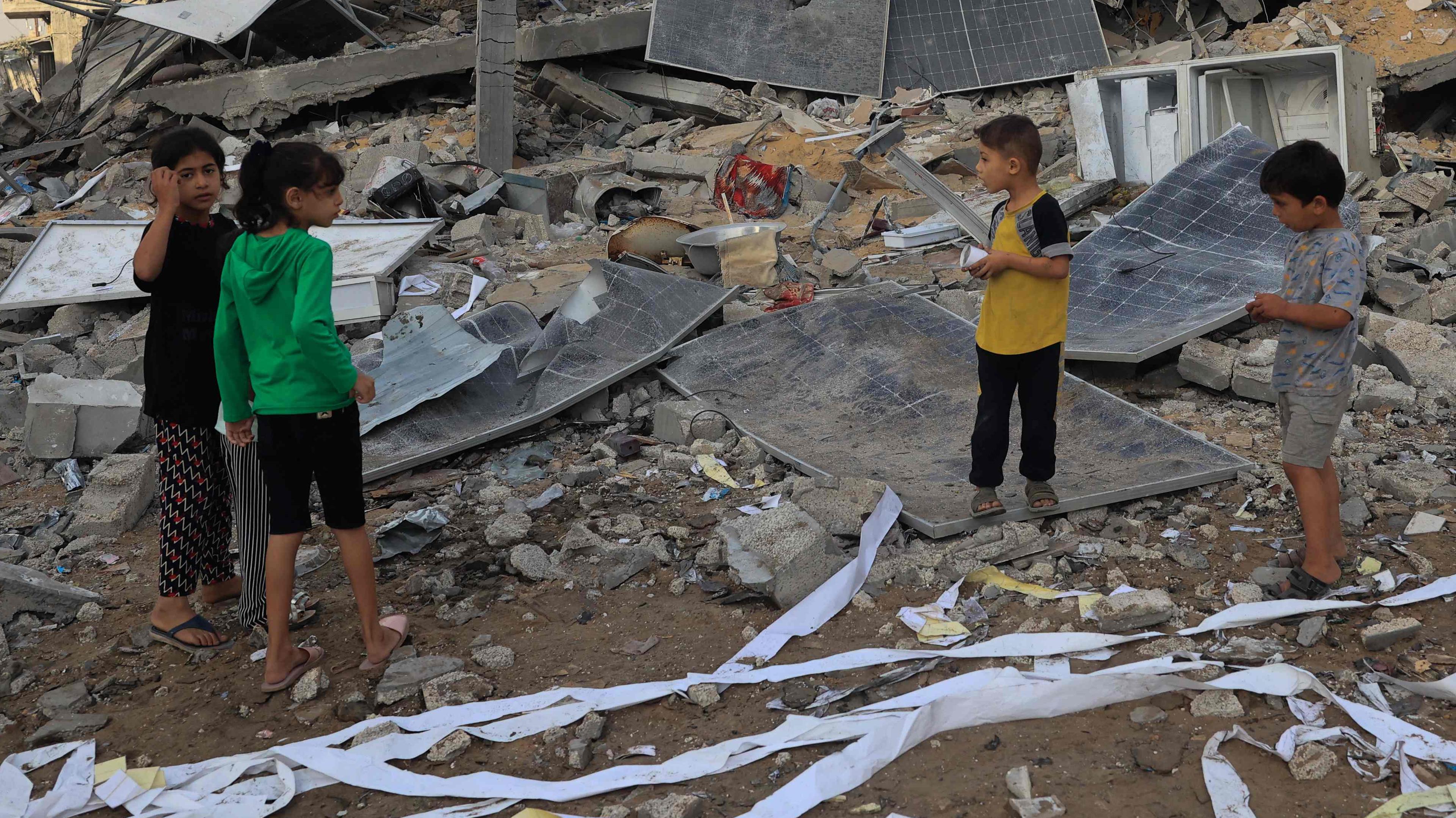Kinder stehen neben einem zerstörten Gebäude in Rafah