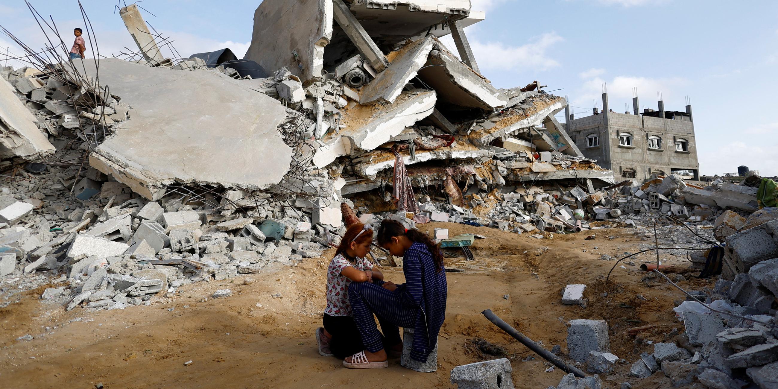 Zwei Kinder sitzen vor den Trümmern eines Hauses in Rafah