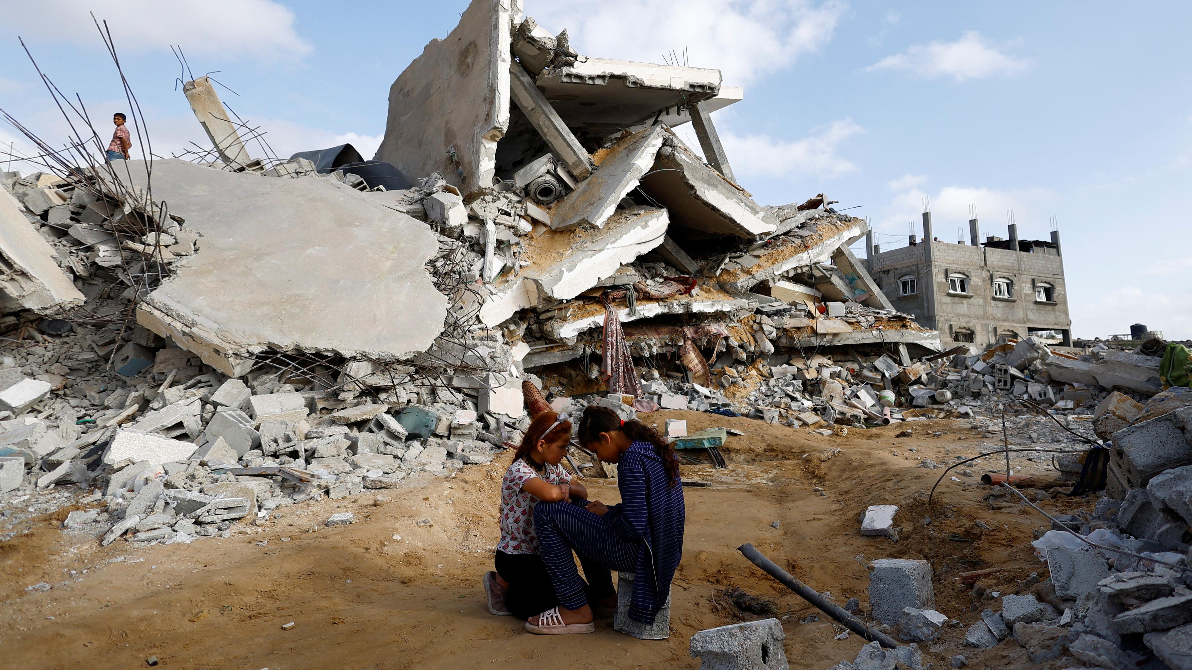 Zwei Kinder sitzen vor den Trümmern eines Hauses in Rafah