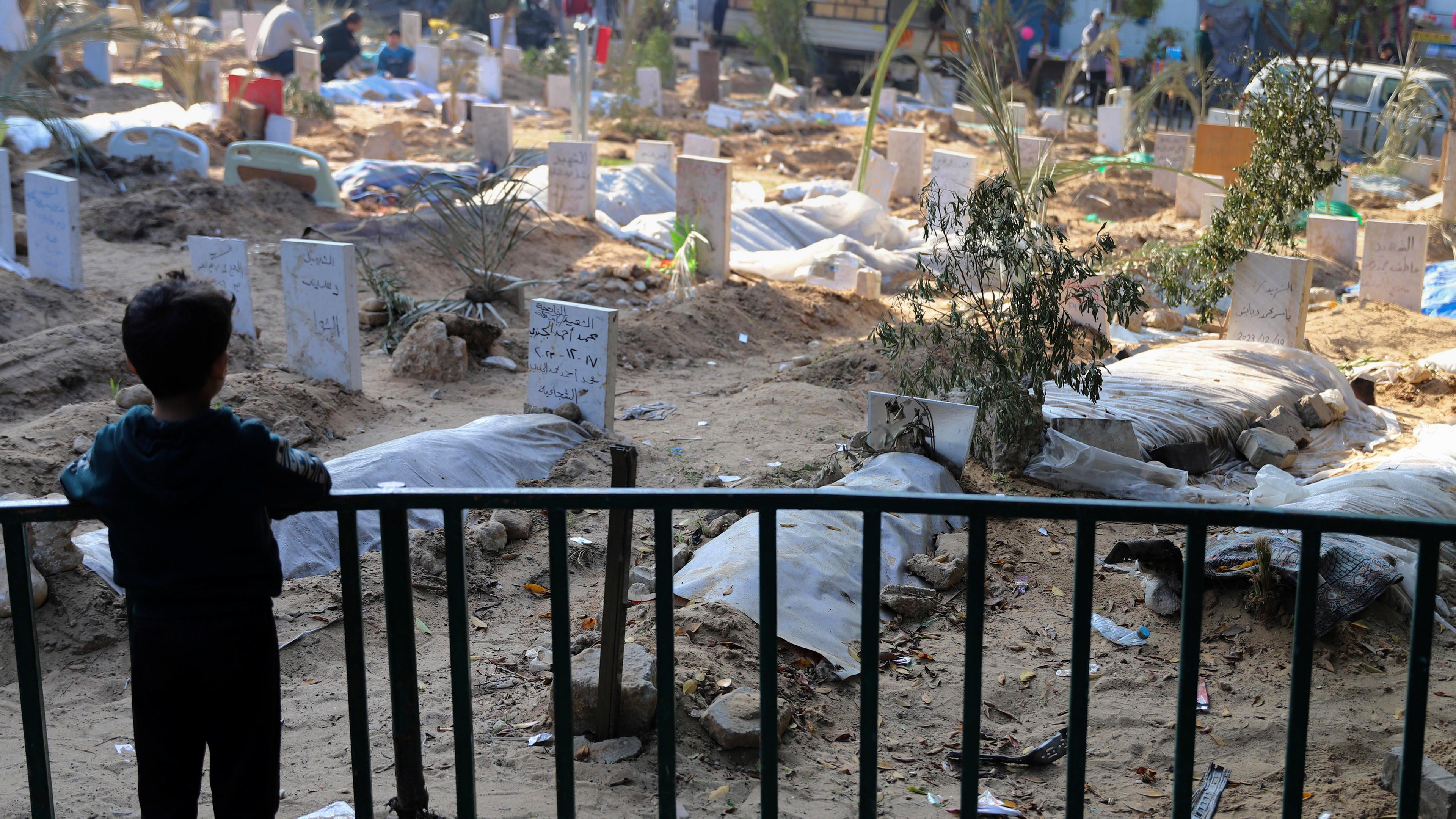 Ein palästinensisches Kind betrachtet die Gräber von Menschen, die bei der israelischen Bombardierung des Gazastreifens getötet und auf dem Gelände des Schifa-Krankenhauses in Gaza-Stadt begraben wurden am 31.12.2023.