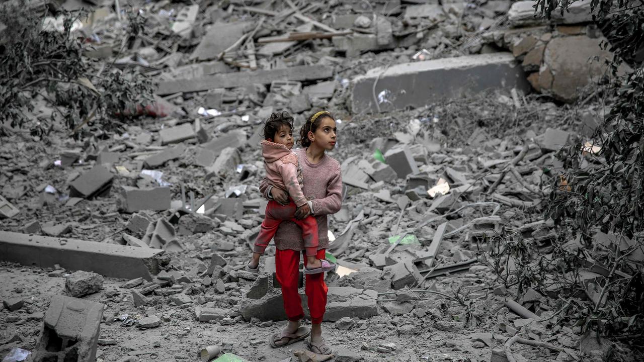 Gaza-Stadt: Ein palästinensisches Mädchen steht inmitten von Trümmern und hält ein kleineres Kind auf dem Arm. 