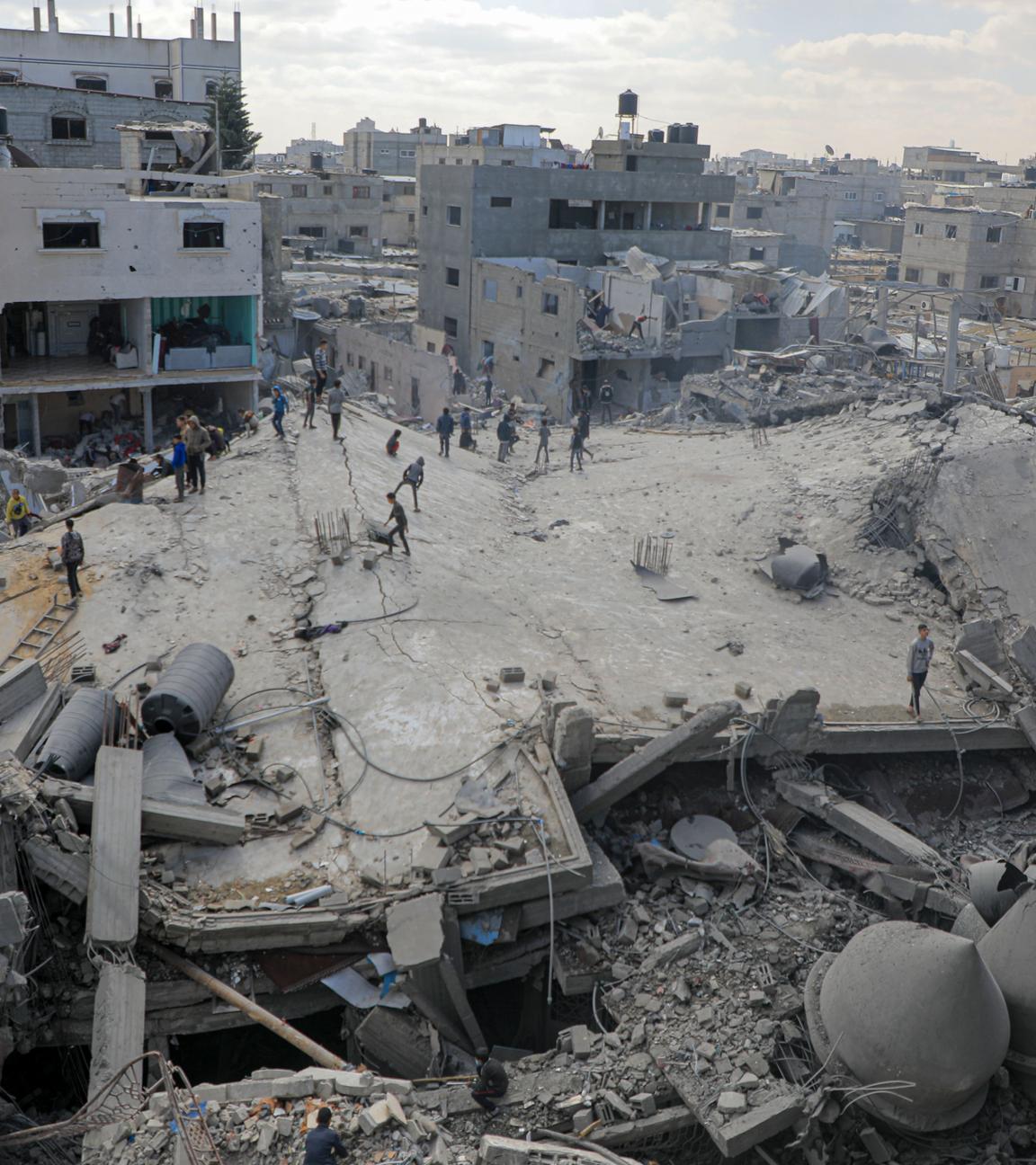 Archiv, 22.02.2024, Palästinensische Gebiete, Rafah: Menschen inspizieren die Trümmer von getroffenen Gebäuden nach einem israelischen Luftangriff in der Stadt Rafah im südlichen Gazastreifen.