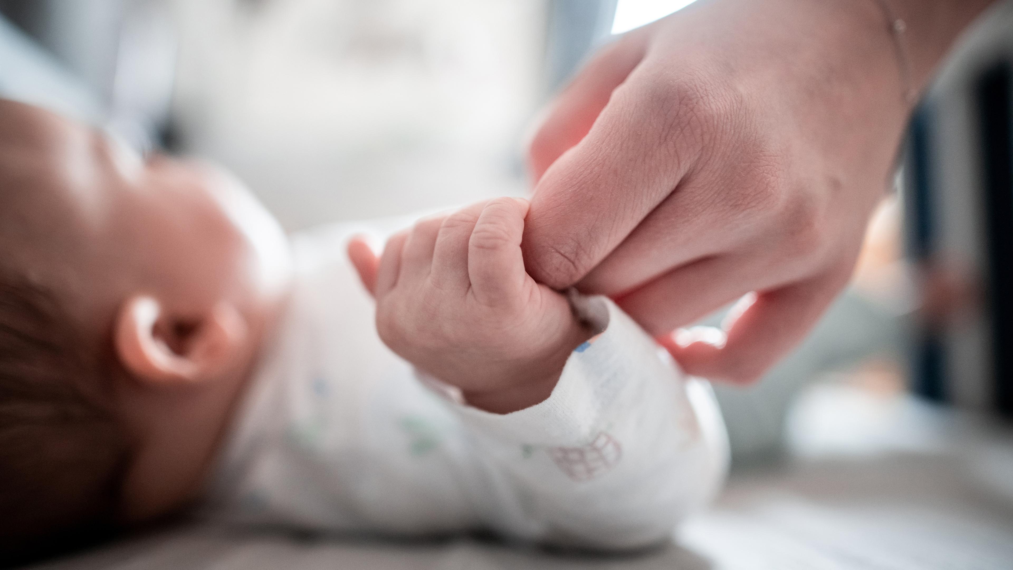 Symbolbild: Baby hält die Finger seiner Mutter