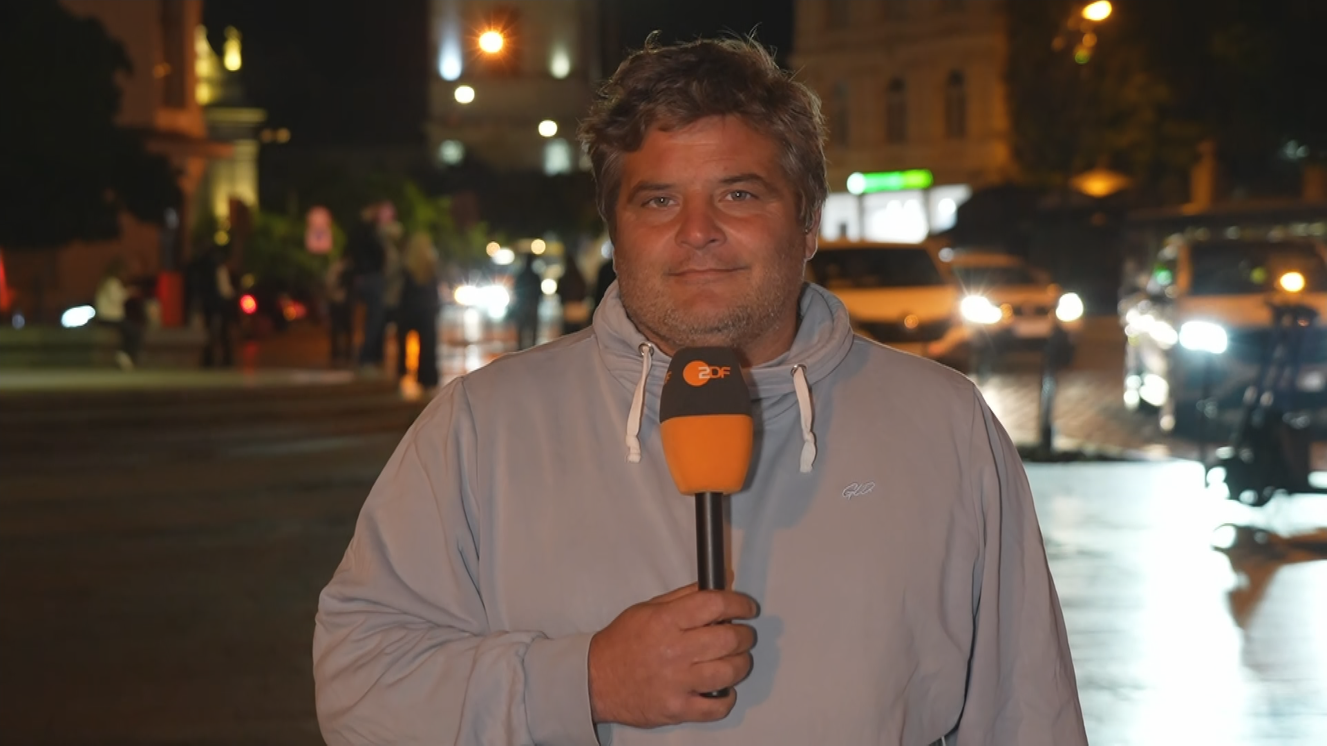 ZDF-Reporter Hassanzadeh vor einer befahrenen Straße nachts.