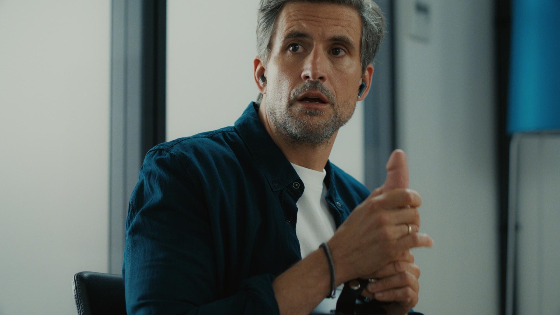 "The other gAIrl – … gegessen wird zuhause": Frank (Tom Beck) sitzt in seinem Büro und hält einen Dildo in der Hand.