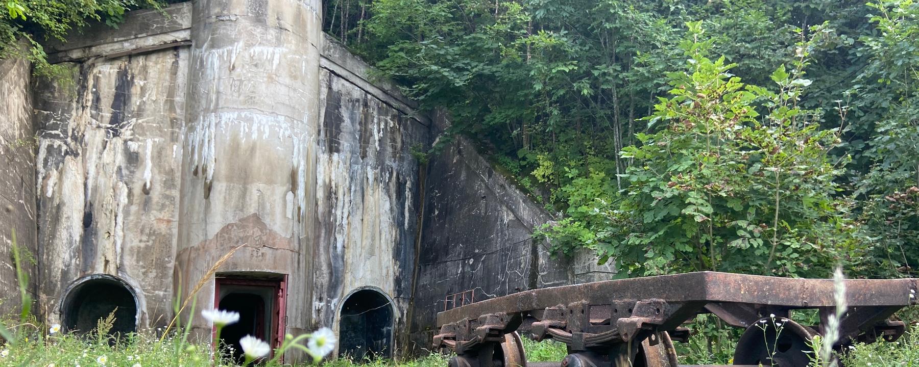 "Geheimes Russland - Wladiwostok": Ein rostiger Karren steht vor einem großen Betonbunker in einem dicht bewachsenen Wald.
