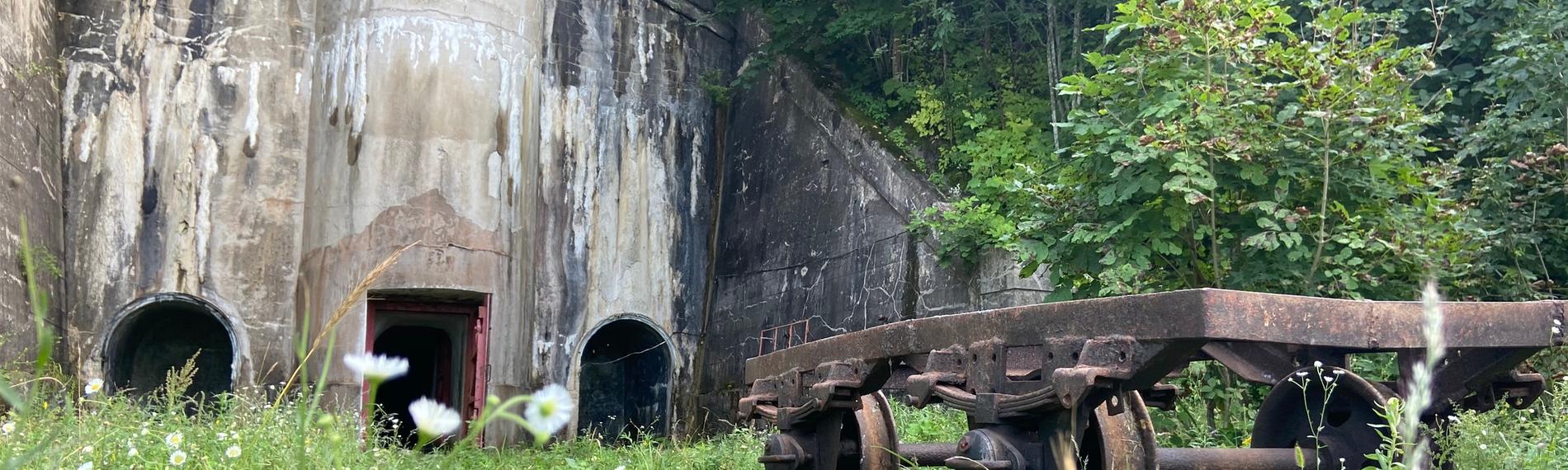 "Geheimes Russland - Wladiwostok": Ein rostiger Karren steht vor einem großen Betonbunker in einem dicht bewachsenen Wald.