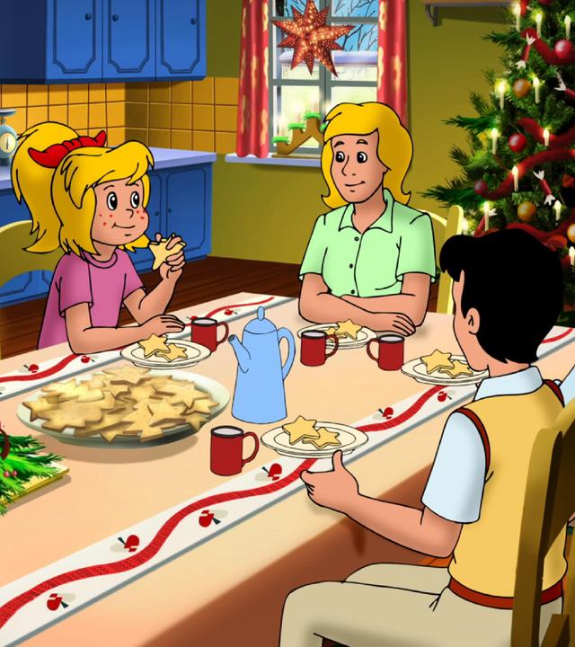 Bibi und Tina und ihre Familie und Freunde sitzen gemeinsam am Tisch und essen Plätzchen. Der Raum ist weihnachtlich geschmückt und im Hintergrund steht ein großer, funkelnder Weihnachtsbaum.