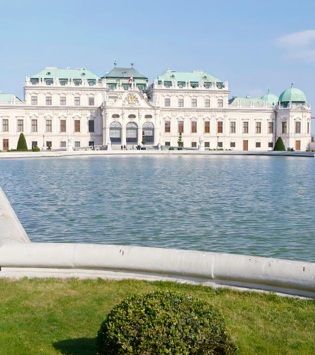 Ansicht des Oberen Belvedere mit Teich und gepflegten Rasenflächen im Vordergrund.