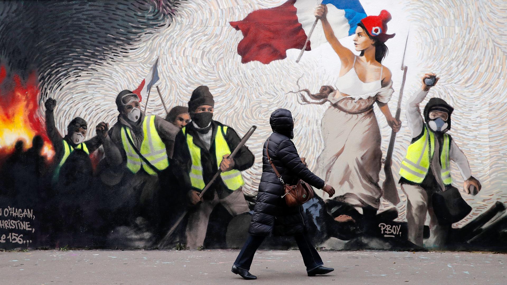 Eine Frau geht an einem Wandbild des Straßenkünstlers Pboy vorbei vorbei