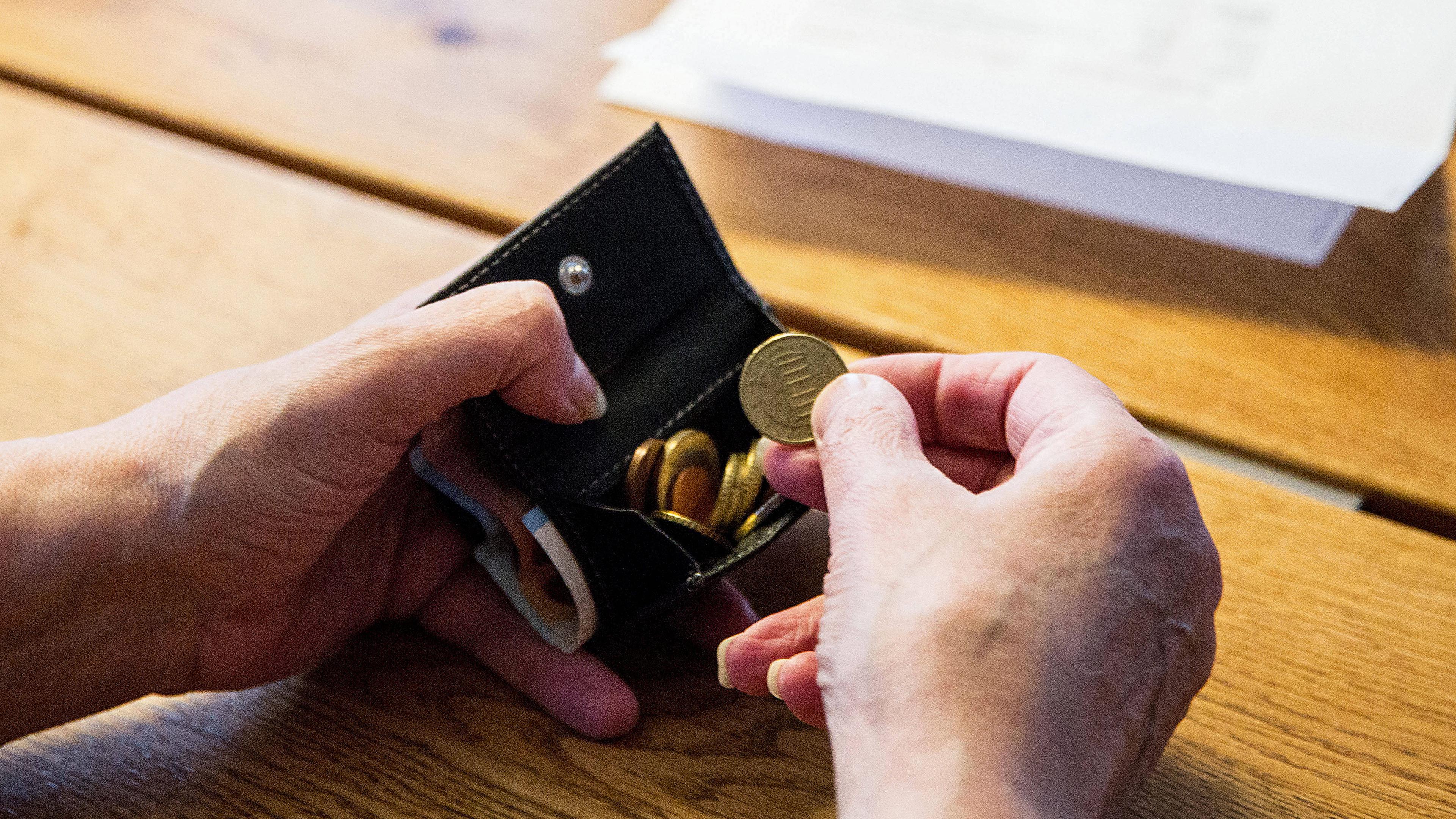 Illustration: Eine Person sitzt an ihrem Tisch und hält eine Geldbörse in den Händen