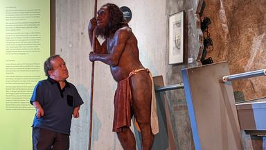 Ausstellungshalle im Neanderthal Museum Mettmann: Martin Müller steht vor einer steinzeitlichen Figur und schaut ihr direkt ins Gesicht.