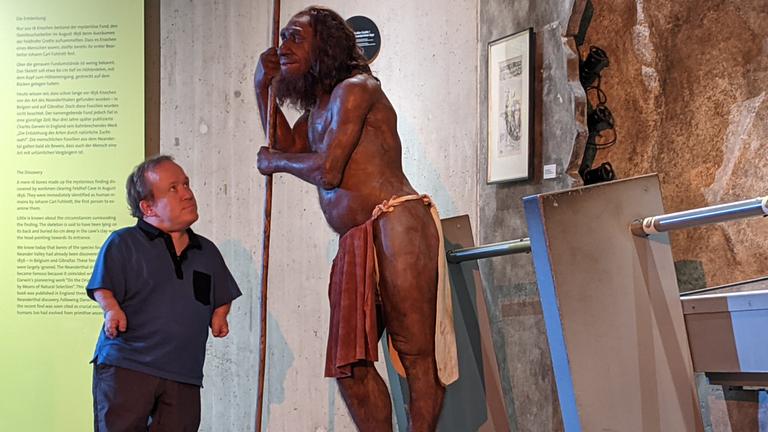 Ausstellungshalle im Neanderthal Museum Mettmann: Martin Müller steht vor einer steinzeitlichen Figur und schaut ihr direkt ins Gesicht.