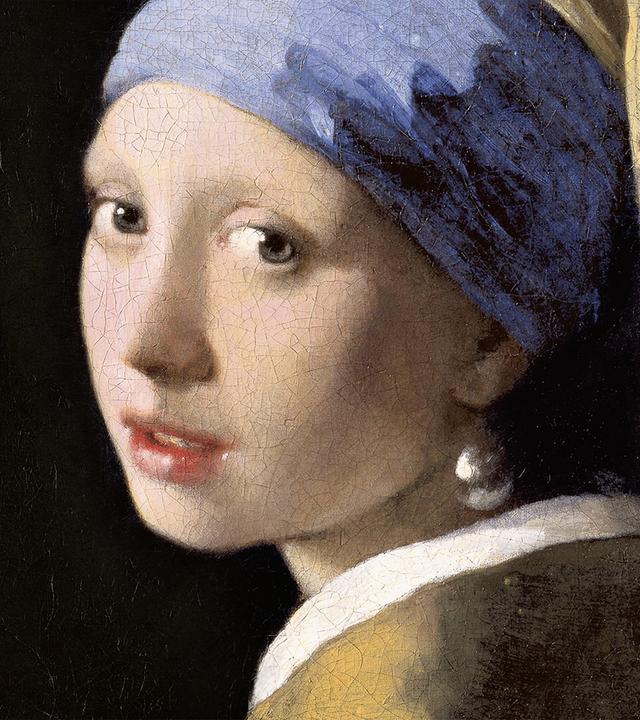 Porträt einer jungen Frau mit blauem und gelbem Kopftuch, gelber Kleidung und einem großen Perlenohrring vor dunklem Hintergrund.