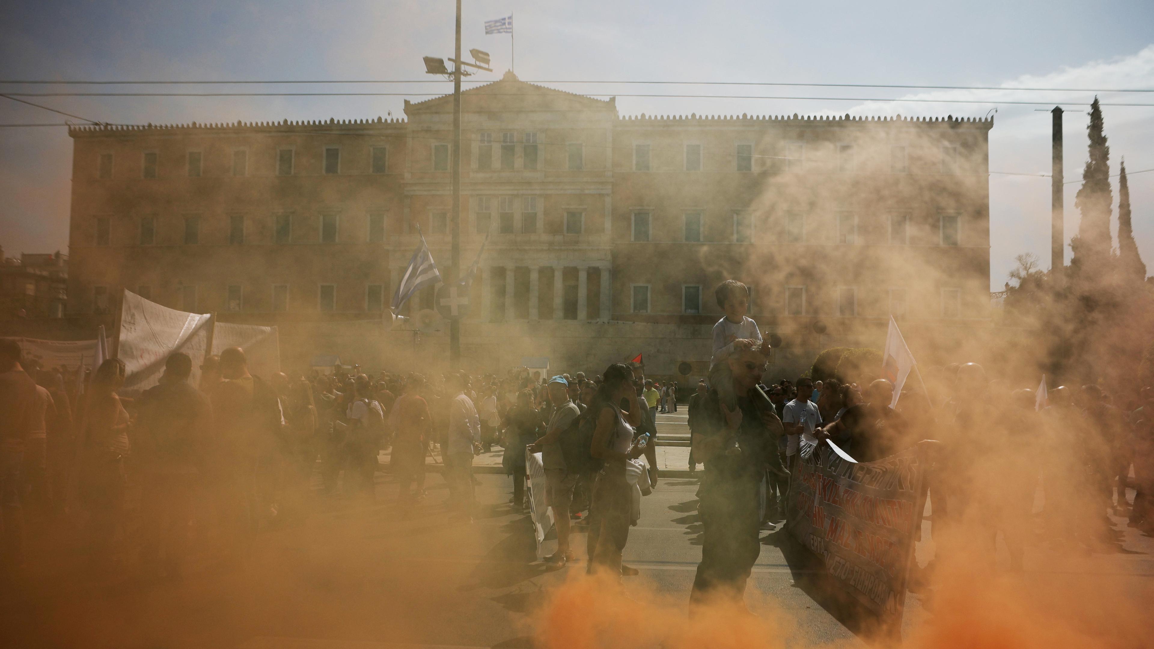 Menschen nehmen an einem Protest teil, während eines 24-stündigen Generalstreiks in Athen. Rauch steigt aus einer Rauchfackel auf.