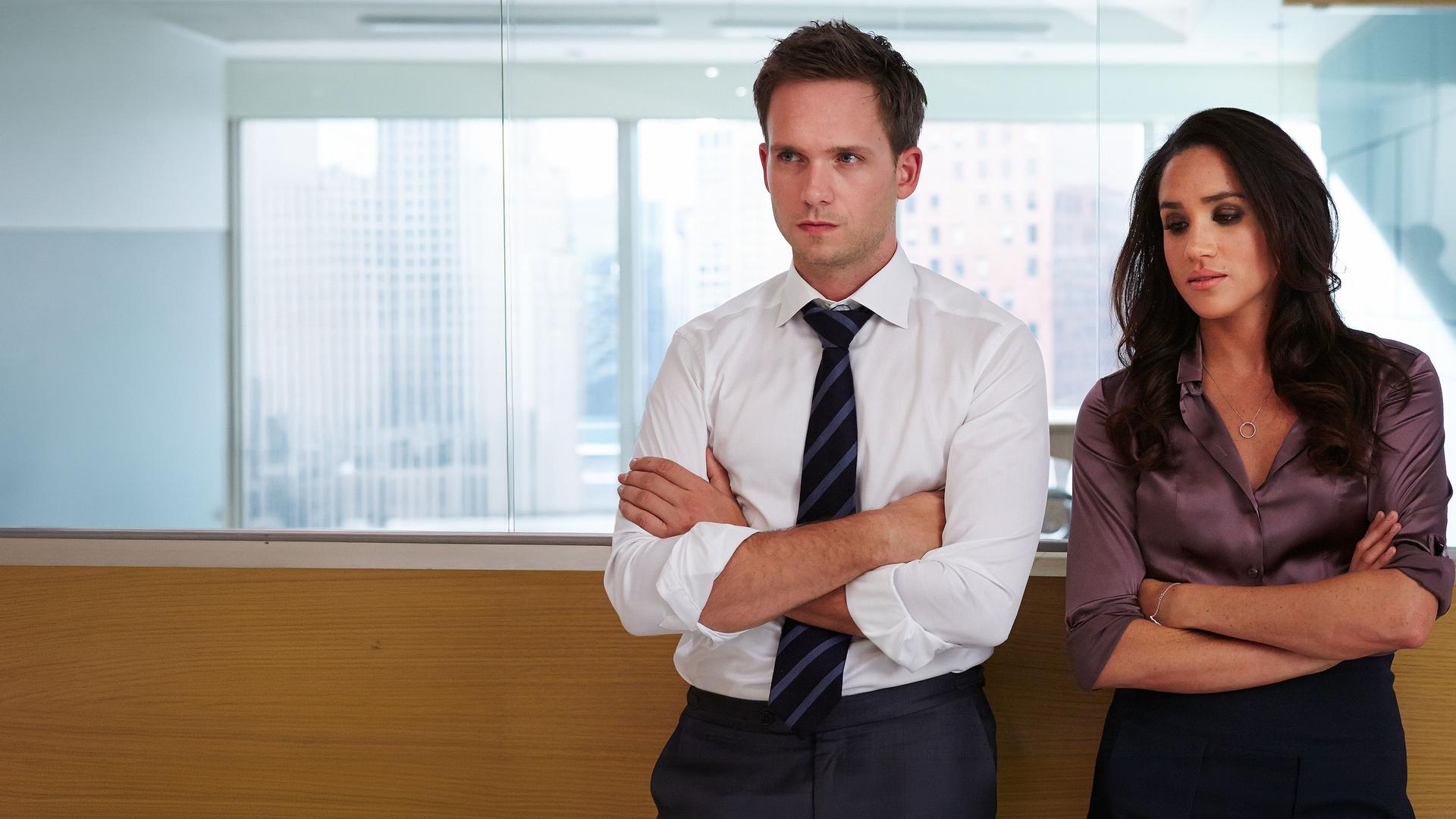"Suits - Genug ist genug": Mike (Patrick J. Adams) und Rachel (Meghan Markle) lehnen an der gläsernen Wand des Konferenzraums. Beide haben die Arme verschränkt und schauen bedrückt.