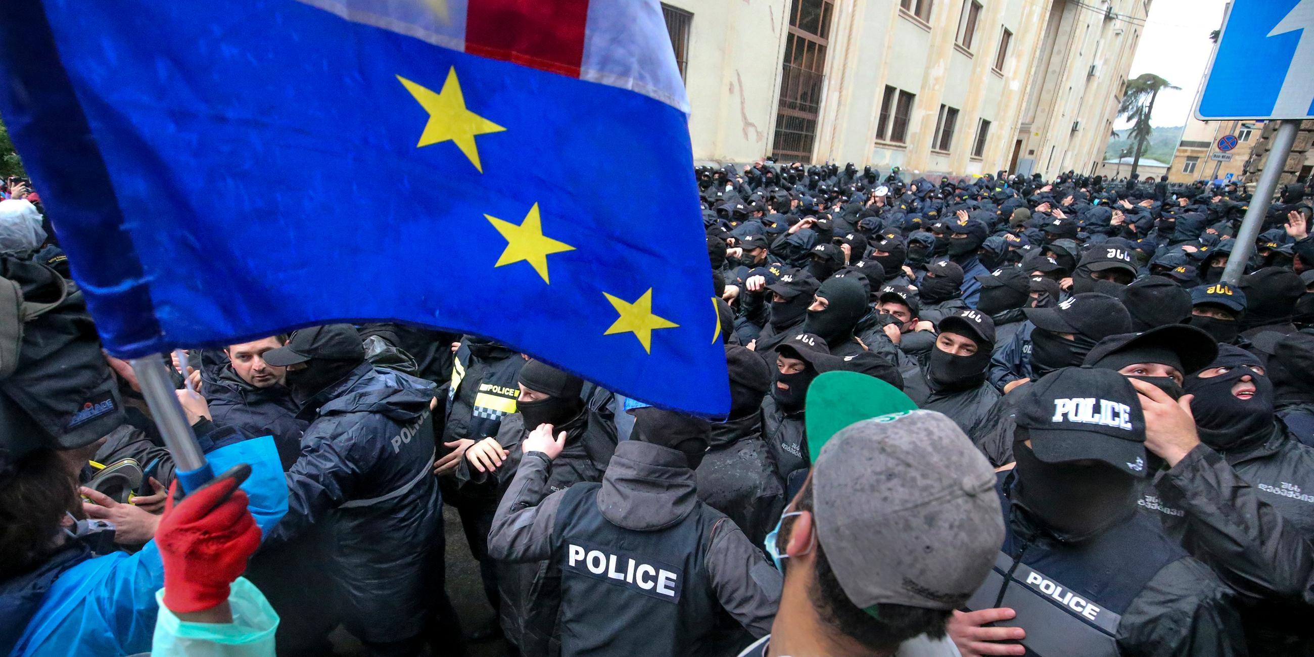 Demonstranten mit georgischen und EU-Flaggen stehen vor einer Polizeisperre in der Nähe des Parlamentsgebäudes in Tiflis