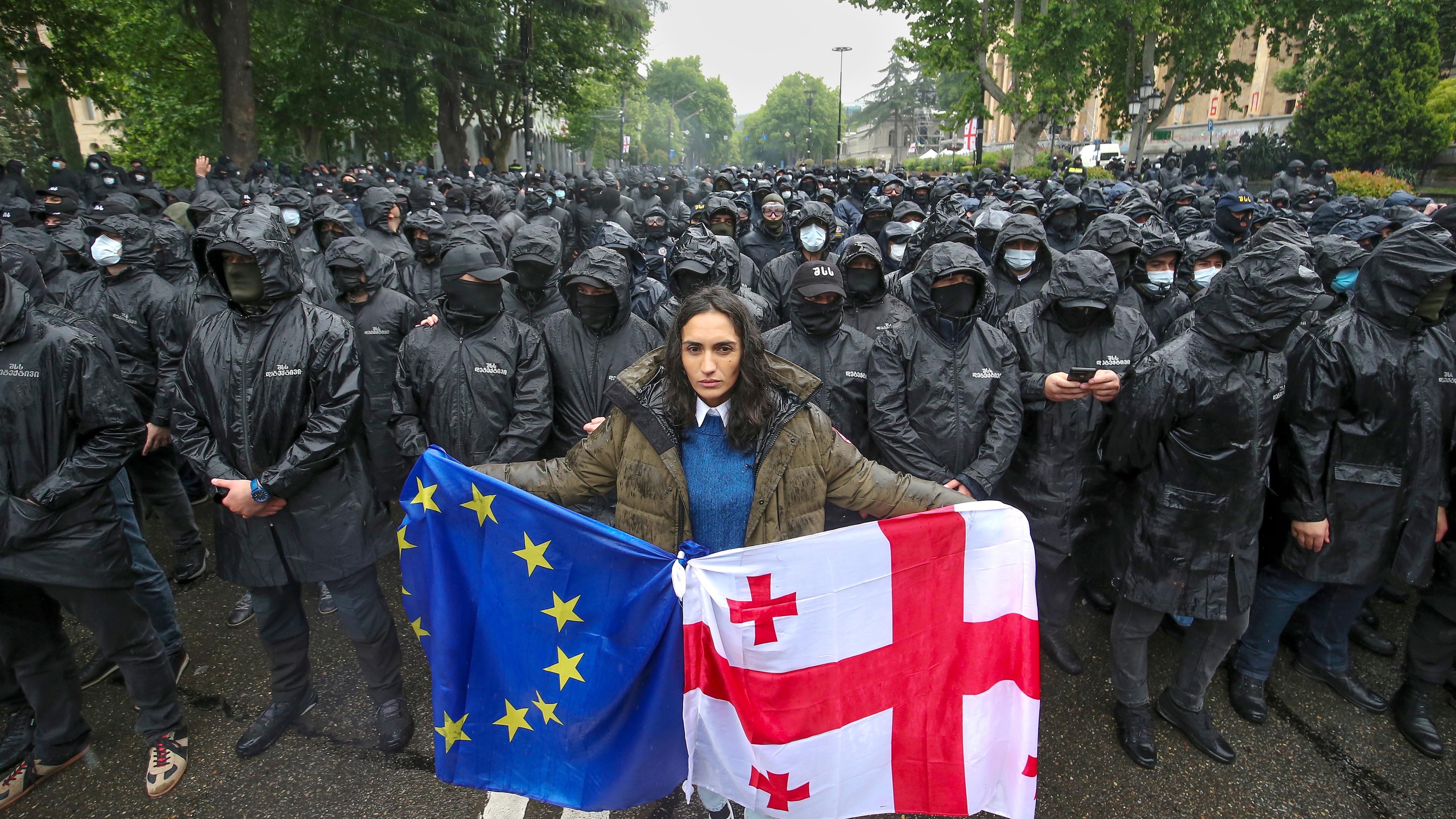 Eine Frau hält einen georgischen und eine EU-Flagge vor Bereitschaftspolizisten, aufgenommen am 14.05.2024 in Tiflis