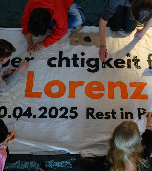 Mitglieder des Bündnisses United against Racism beschriften ein Transparent für die Kundgebung Gerechtigkeit für Lorenz.