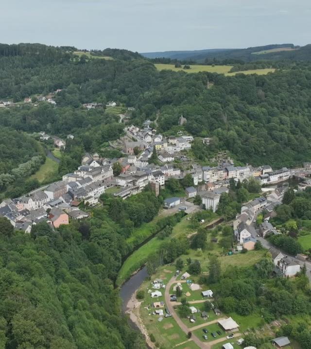 Luftaufnahme von Häusern mehrerer Wohnsiedlungen umgeben von Wald.