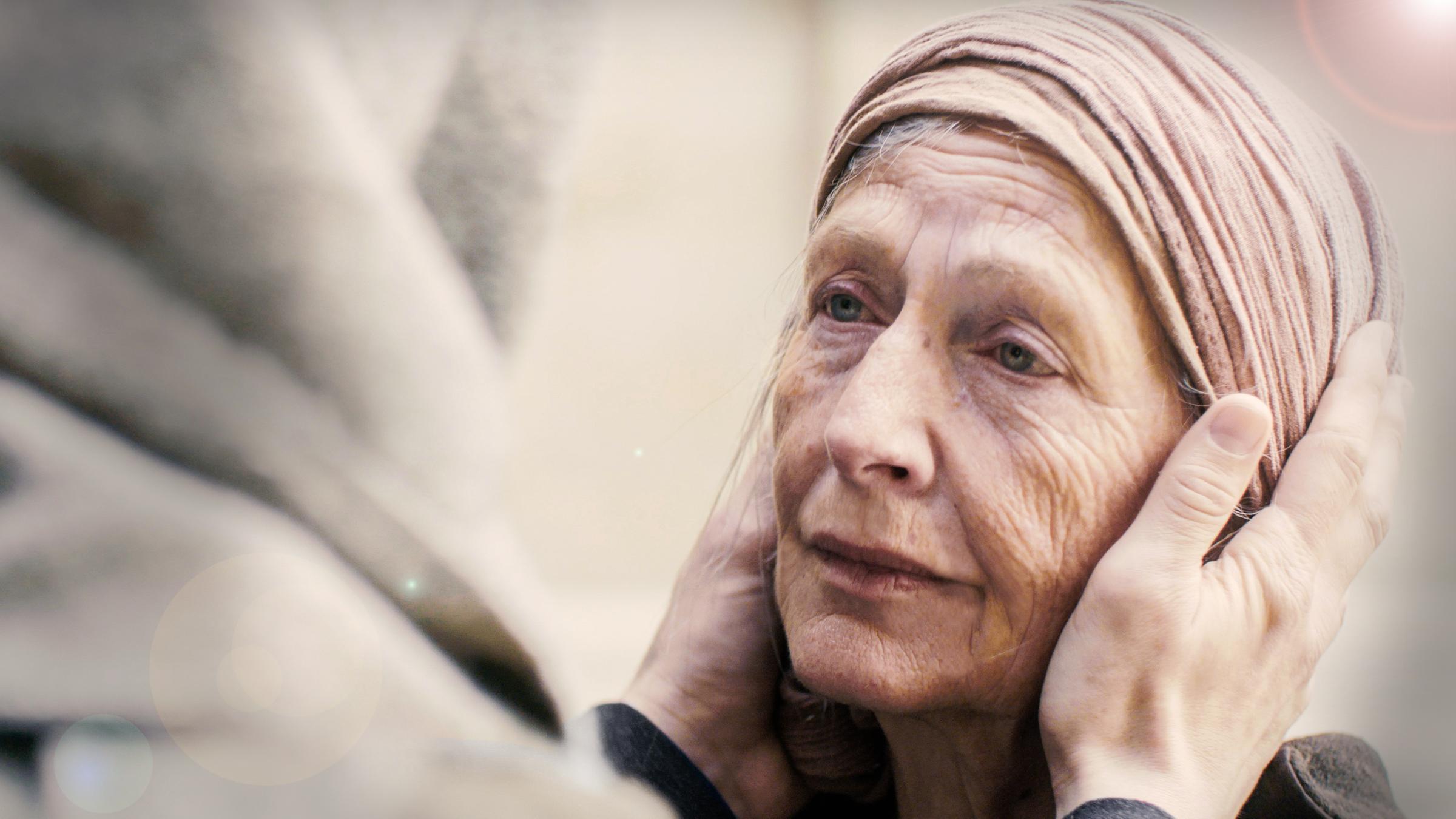 Alte Frau wird mit den Händen am Kopf angefasst